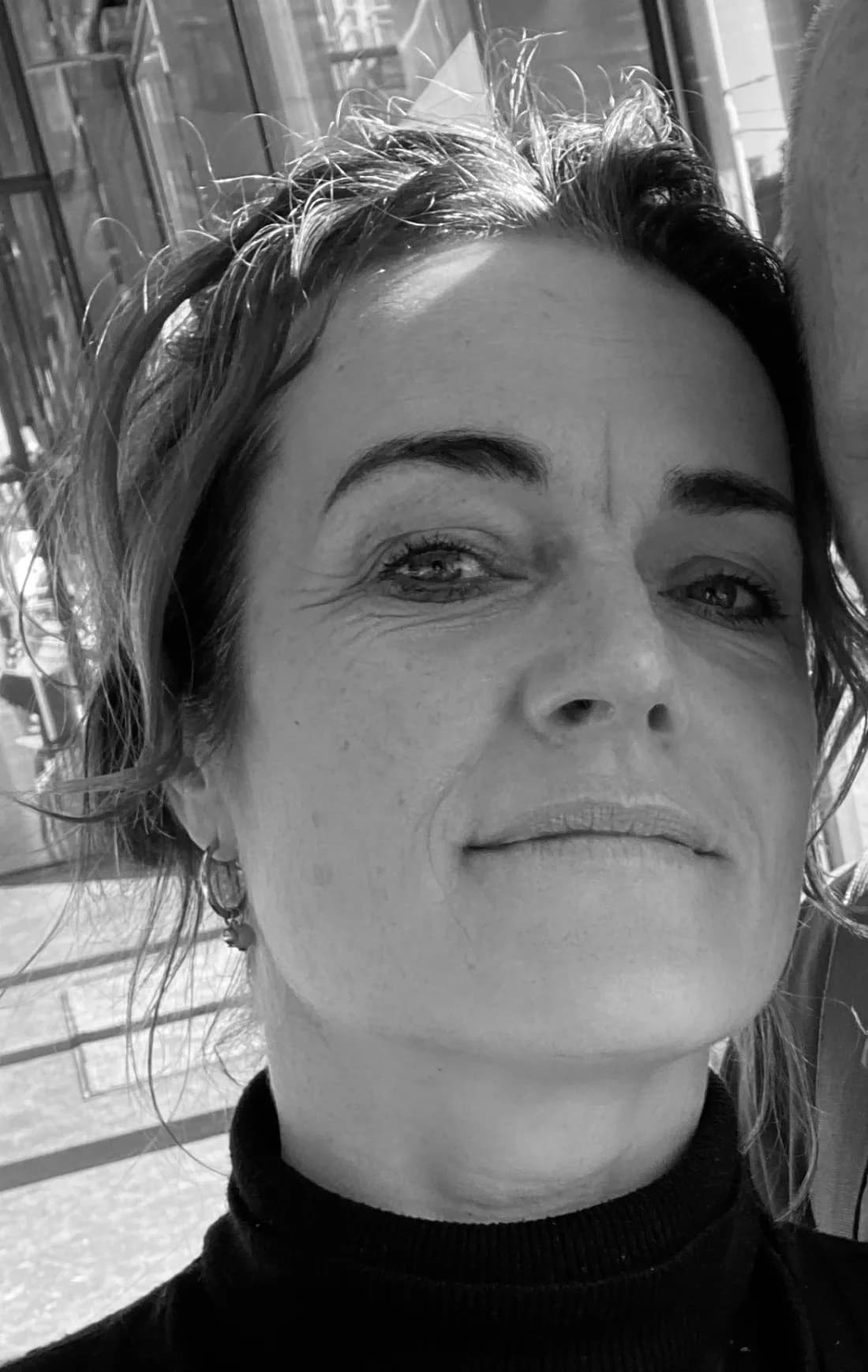 Judith Nab in zwart-wit, close-up voor een winkelruit.